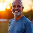 Ritratto energico di Marco Rossi, 55 anni, con badge di 'Appassionato Fitness', in una palestra moderna e pulita.
